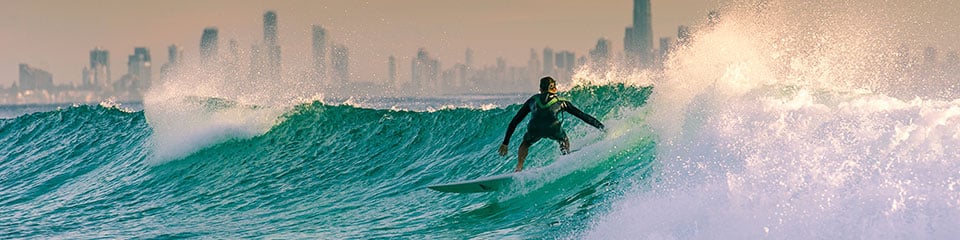 Surfer with Gold Coast City skyline in the background.